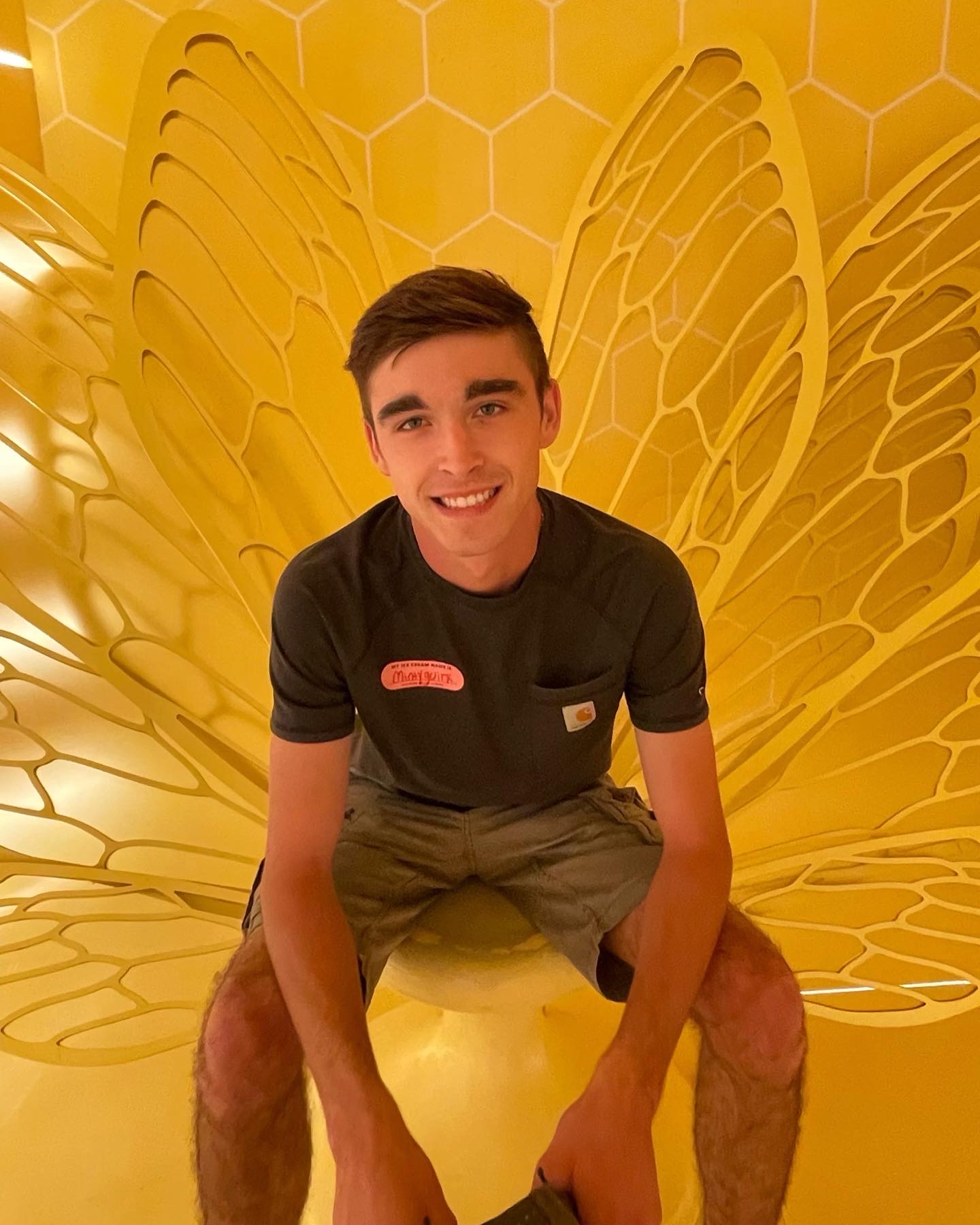 A picture of Aaron sitting down in a yellow chair at the ice cream museum in New York City.