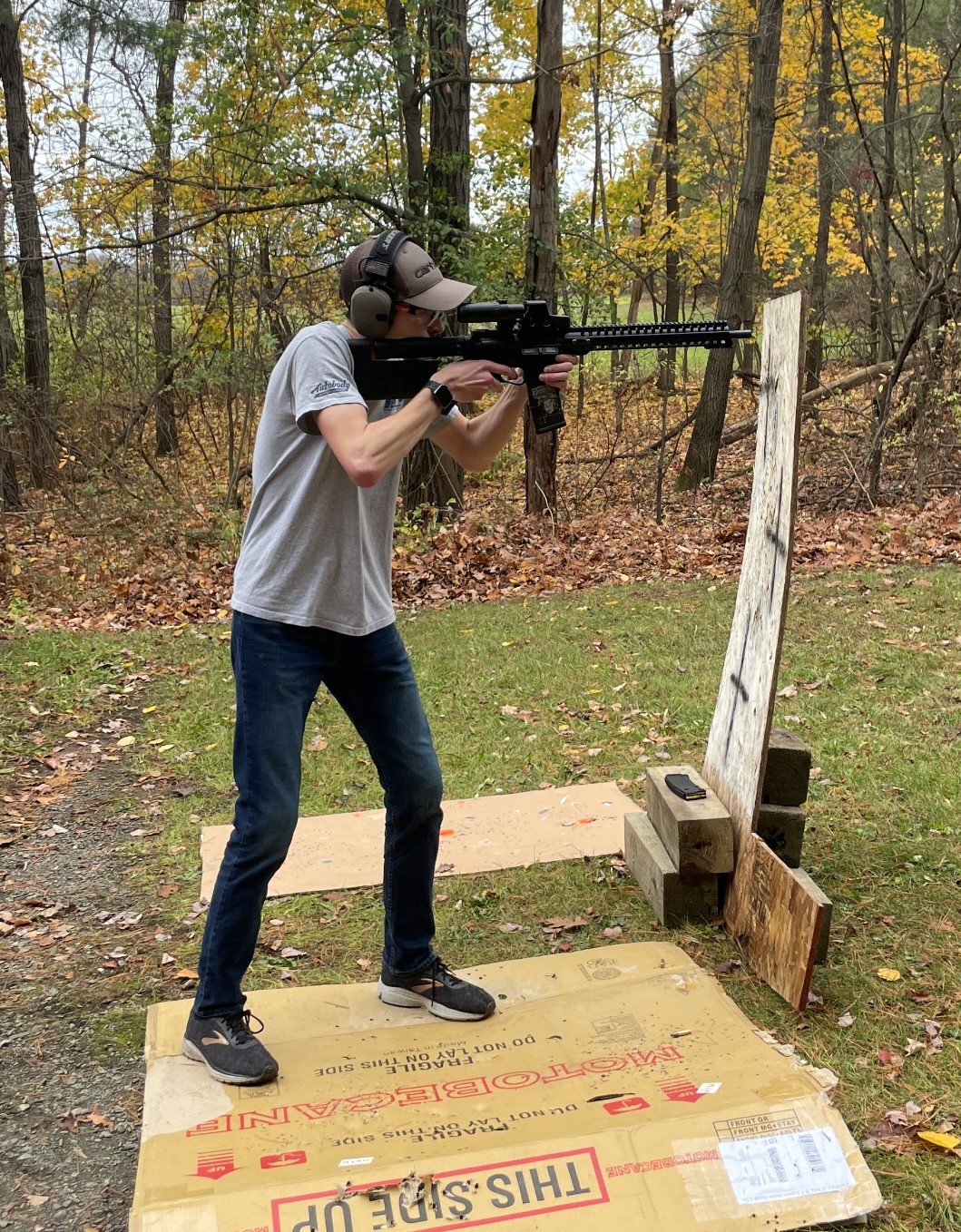 A picture of Aaron holding a rifle at an outdoor shooting range.